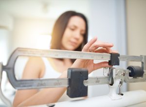 Shot of a young woman weighing herself on a scale
