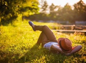 hipster laying in a grass lawn at sunset - self love