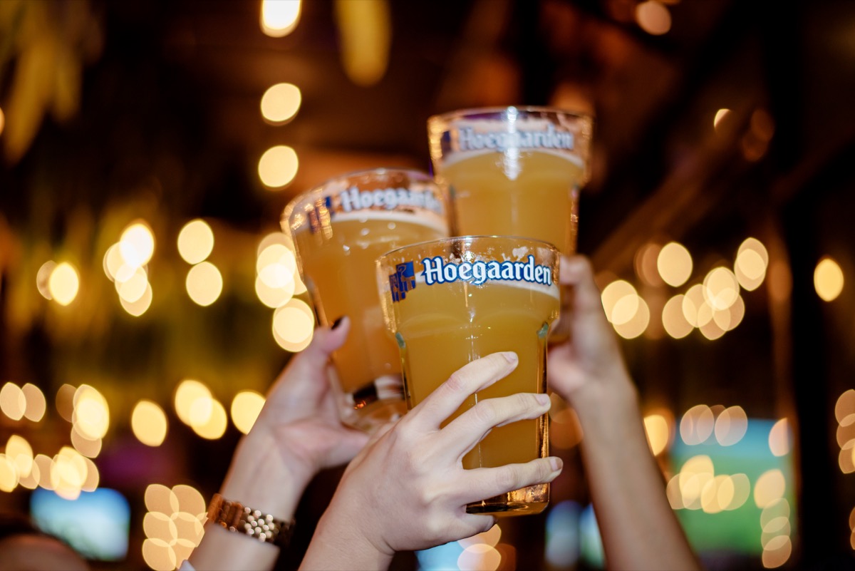 Hoegaarden beer cups in the air for a cheers