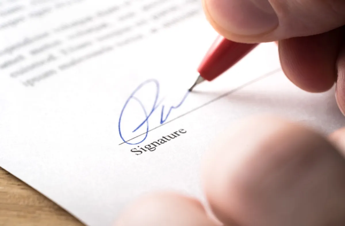 close up of someone signing a contract