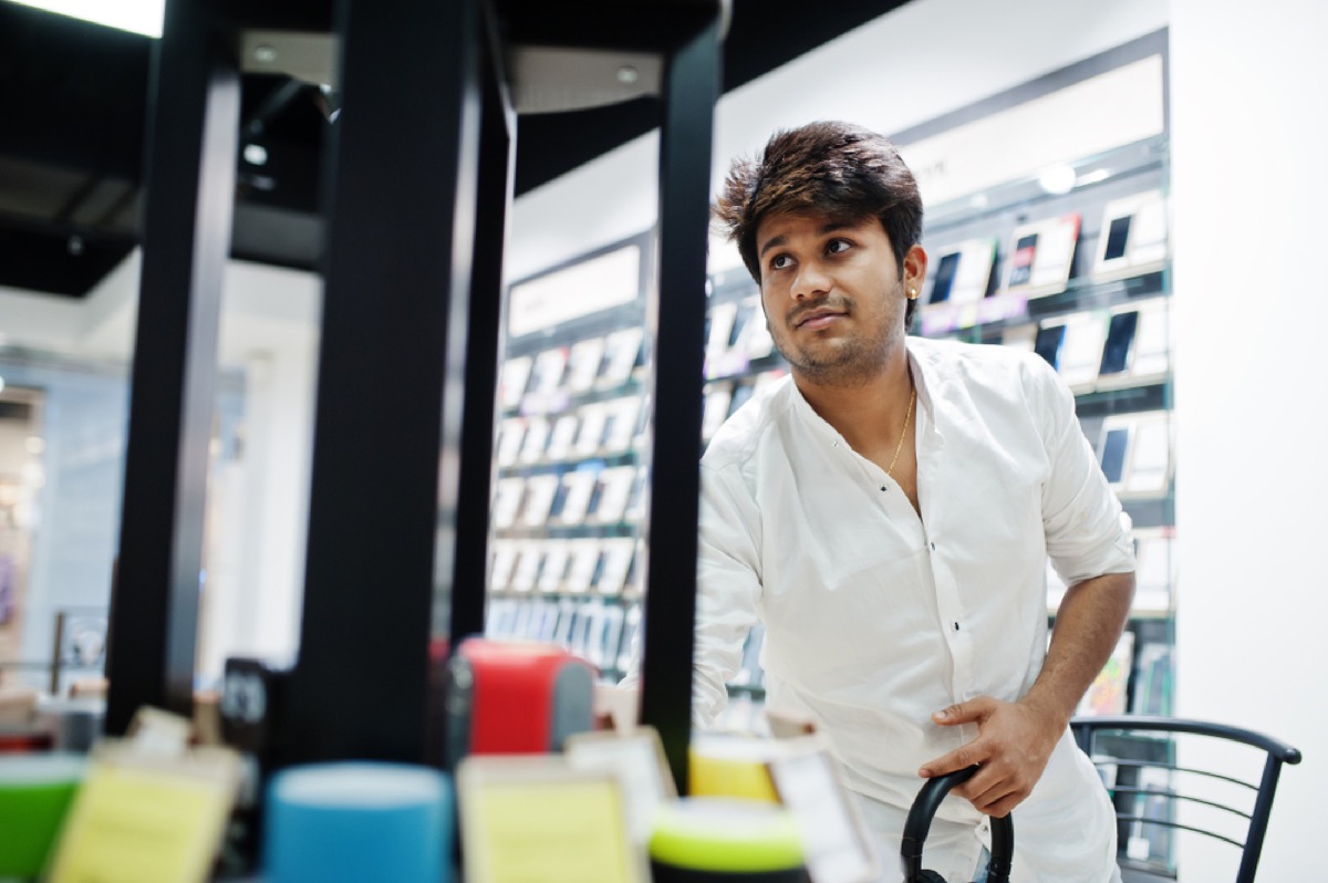 indian man looks at phone at electronic store