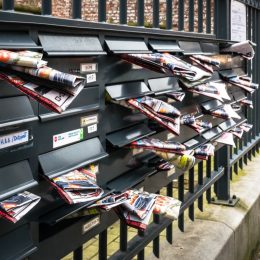 junk mail stuffed in the mailboxes of an apartment complex in brussels