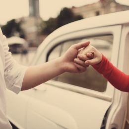 man helping woman out of her care in an old fashioned type photo