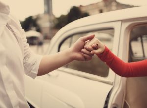 man helping woman out of her care in an old fashioned type photo