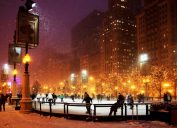 people ice skating in chicago during a snow storm at night