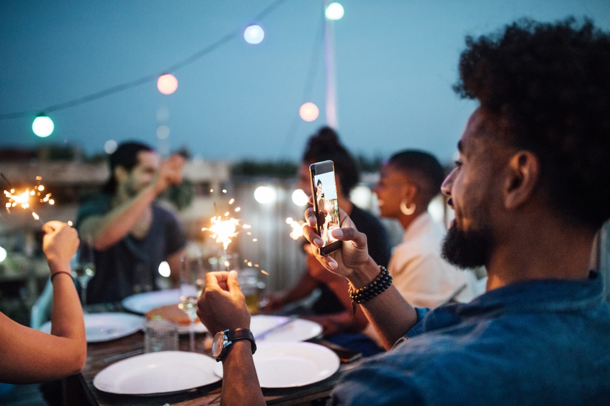 man taking a picture of sparkler at a party on his phone
