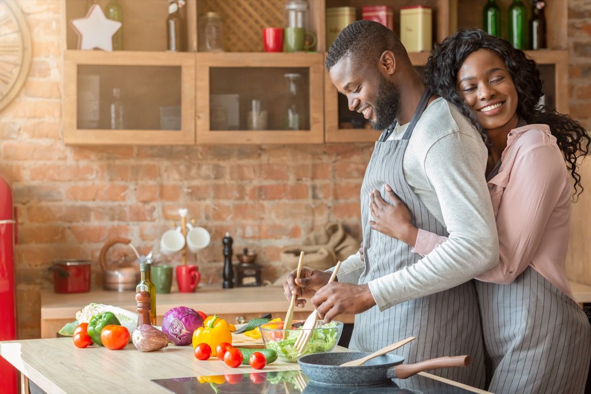 Wife hugging her husband from behind and showing her gratitude for his cooking