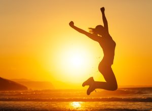 woman jumping into air on beach at sunset, monday quotes