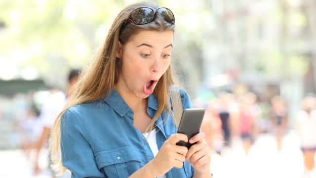 Woman on phone surprised reading viral dating story