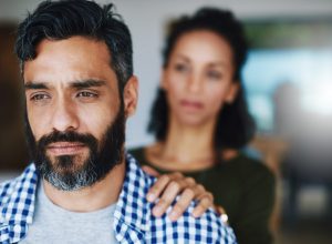 Shot of a woman comforting her distraught husband at home by putting her hand on his shoulder