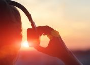 woman putting on over-ear headphones at sunset - sound facts
