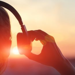 woman putting on over-ear headphones at sunset - sound facts