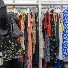 woman shops through rack of clothing