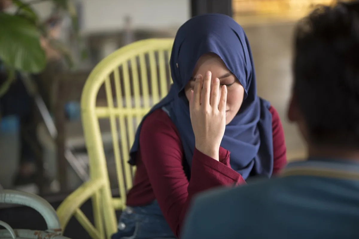 Young Muslim woman upset, holds head in hand