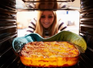 Woman taking a casserole out of the oven