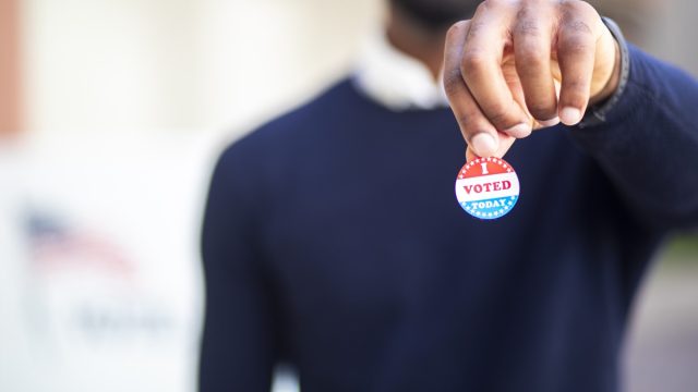 a young black man with his I voted sticker after voting in an election.