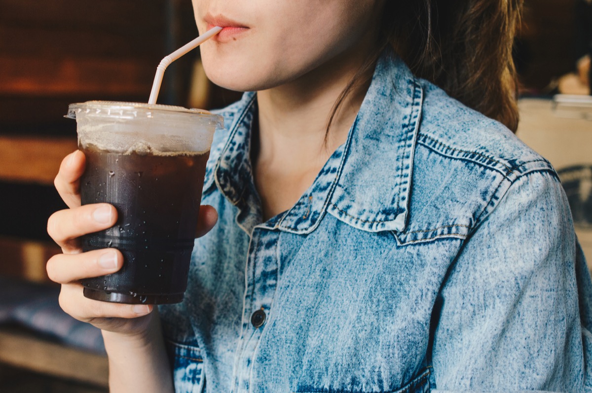 close up of woman drinking black iced coffee