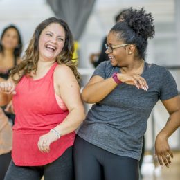 white woman and black woman dancing together at an exercise class