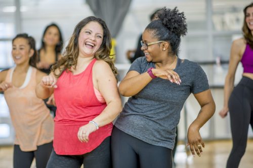 white woman and black woman dancing together at an exercise class
