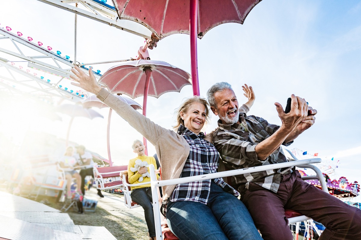 older white couple taking a selfie on a carnival ride