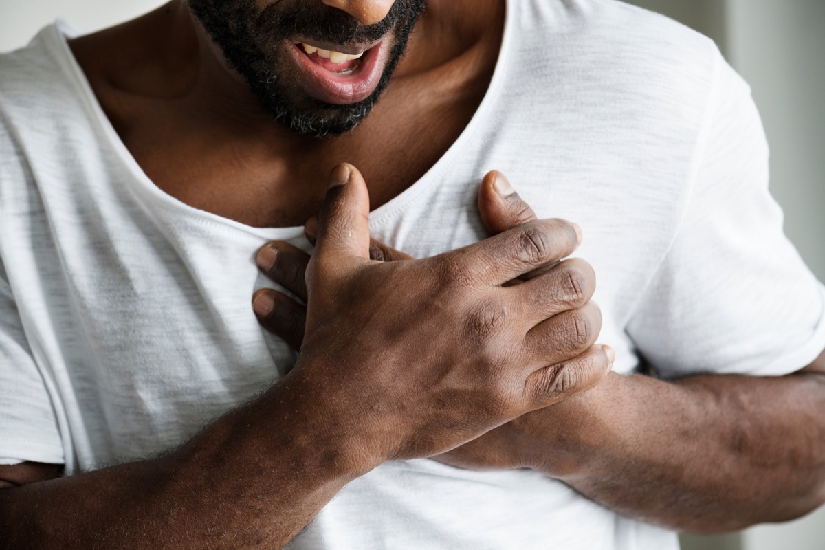 man squeezing his chest with heart problems