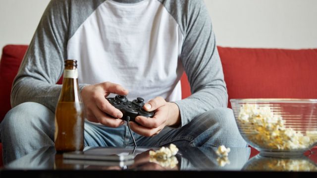 Man playing video games on the sofa after calling in sick to work