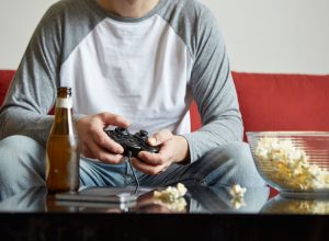 Man playing video games on the sofa after calling in sick to work