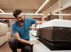 Man Inspecting a Mattress While Shopping, https://bestlifeonline.com/body-sleep/