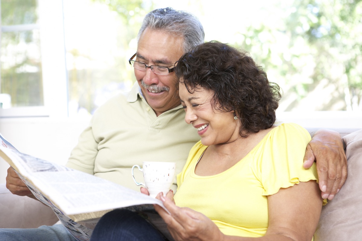 Older couple happily reading newspaper