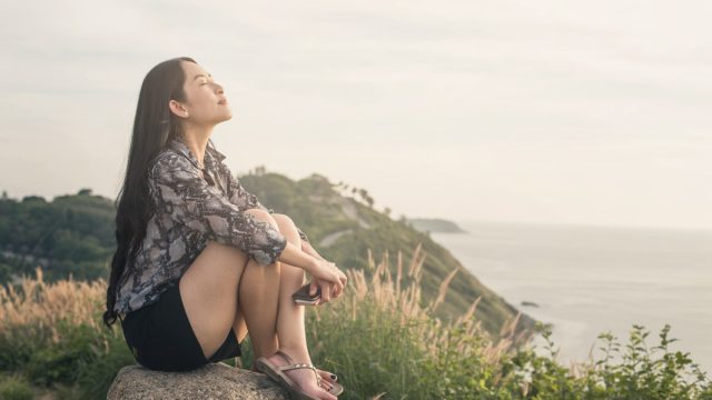 relaxed woman sitting in the grass by the ocean
