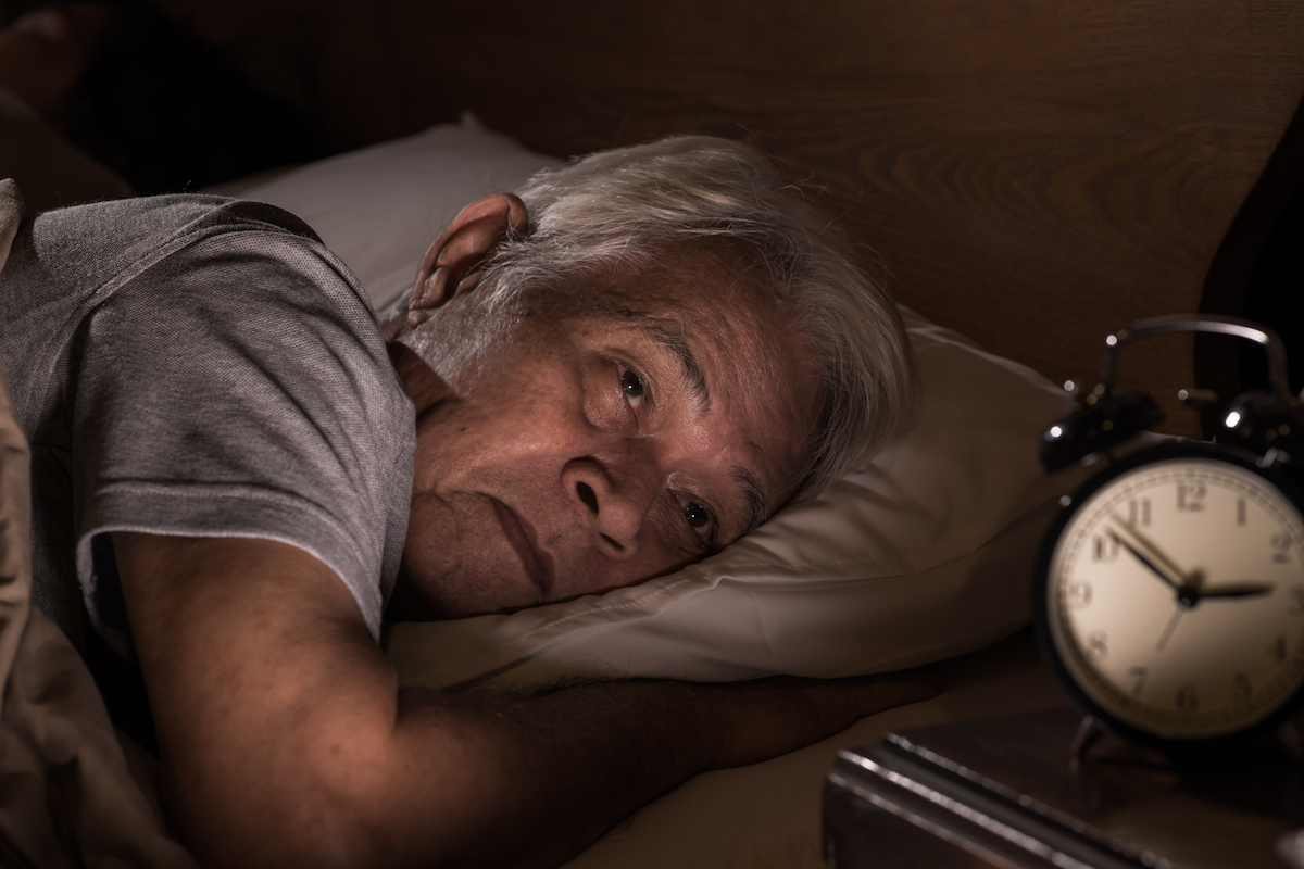 senior asian man lying in bed cannot sleep from insomnia