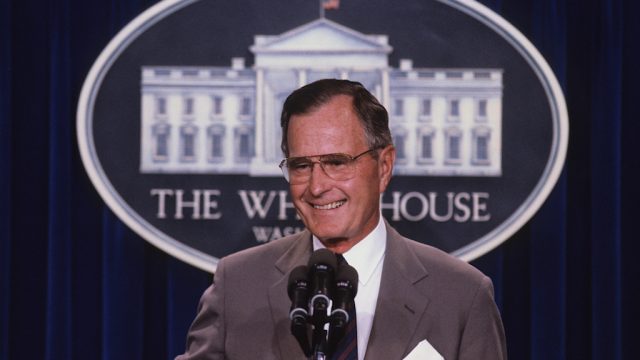 george h.w. bush tands at the podium as he responds to reporters questions during a news conference in the press briefing room at the White House in 1990.