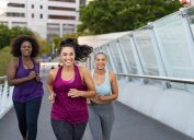Curvy multiethnic young women jogging together on city bridge