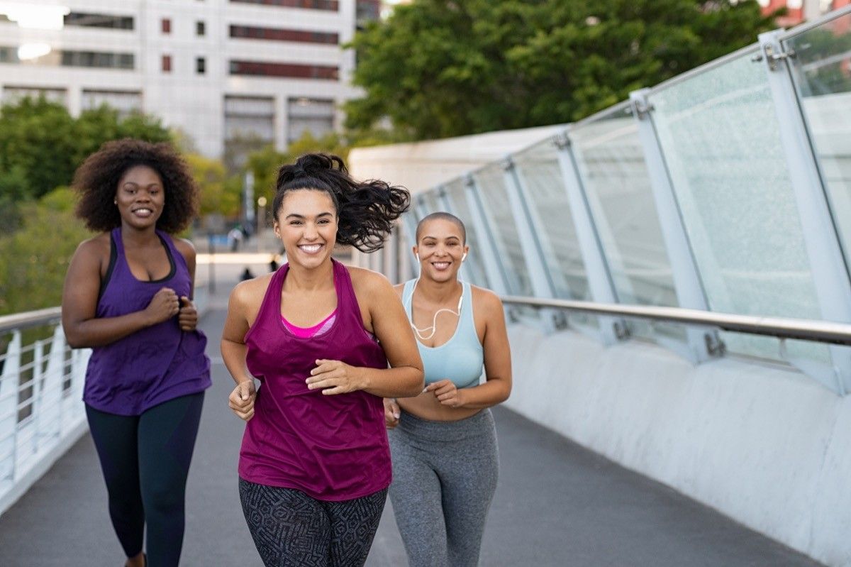 Winding multi-ethnic young women jogging together on a city bridge