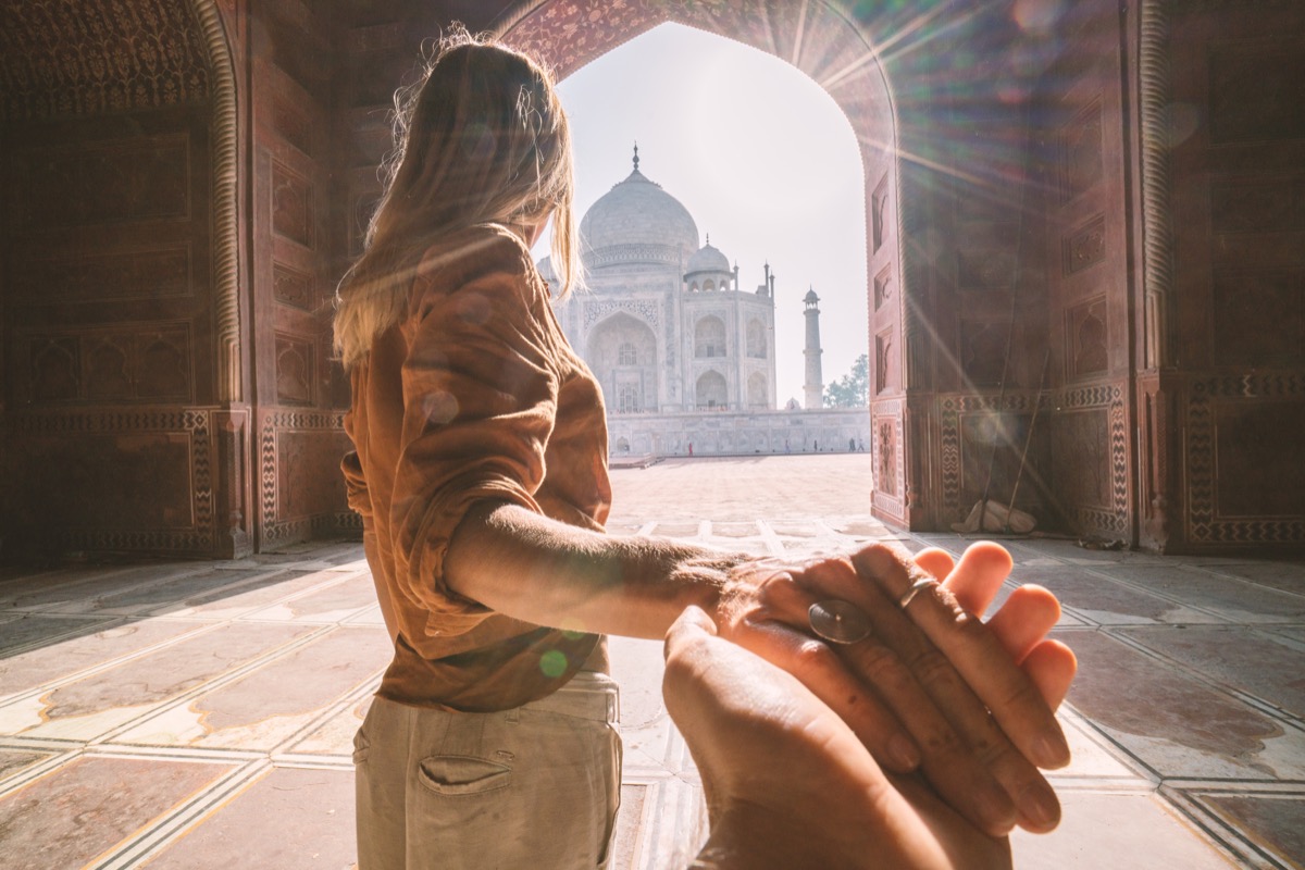 follow me to the Taj Mahal, India. Female tourist leading boyfriend to there magnificent famous Mausoleum in Agra. People travel concept