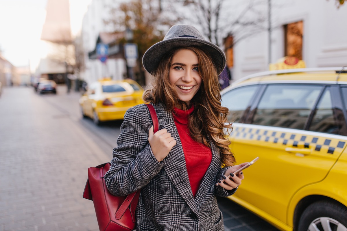 woman in a tweed jacket standing in front of a taxi