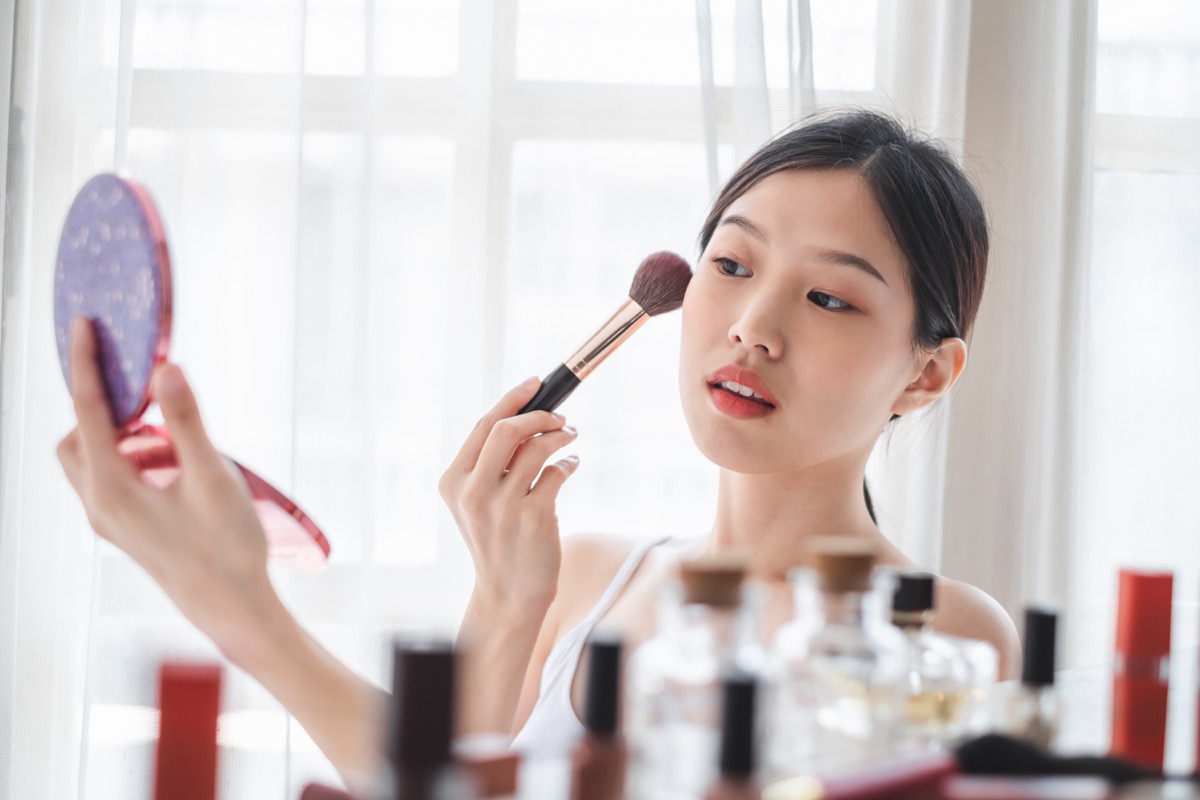 Young beautiful woman applying cosmetics make up on her face, health beauty skin care and make up concept
