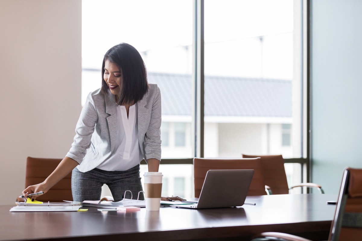 Woman smiling at work looking down at her notebook