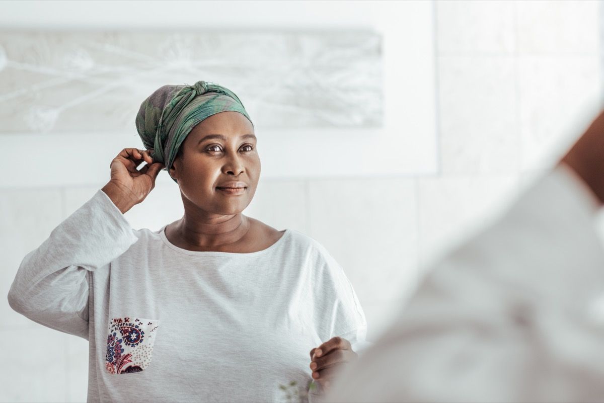 older woman over 40 smiling at herself in the mirror