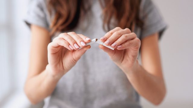 woman snapping a cigarette in half and quitting smoking, look better after 40