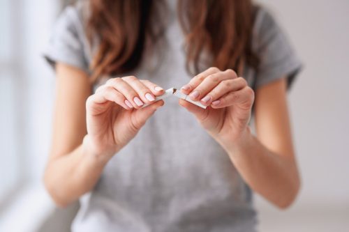 woman snapping a cigarette in half and quitting smoking, look better after 40