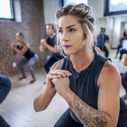 Diverse group of young adults doing squats in unison during a fitness class