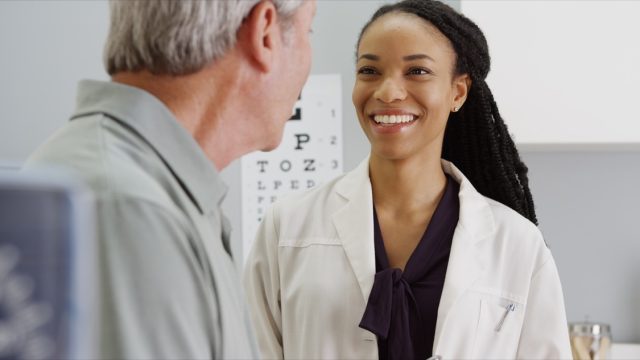 young black female doctor talking to older white male patient