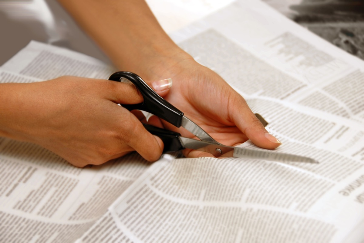 white hands cutting newspaper