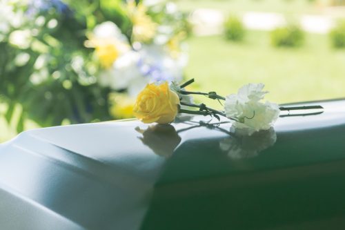 A closeup of flowers atop a funeral casket outdoors, things you should never lie to kids about