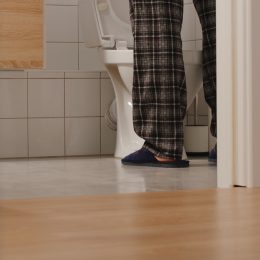 man's legs in pajamas while he pees in a toilet