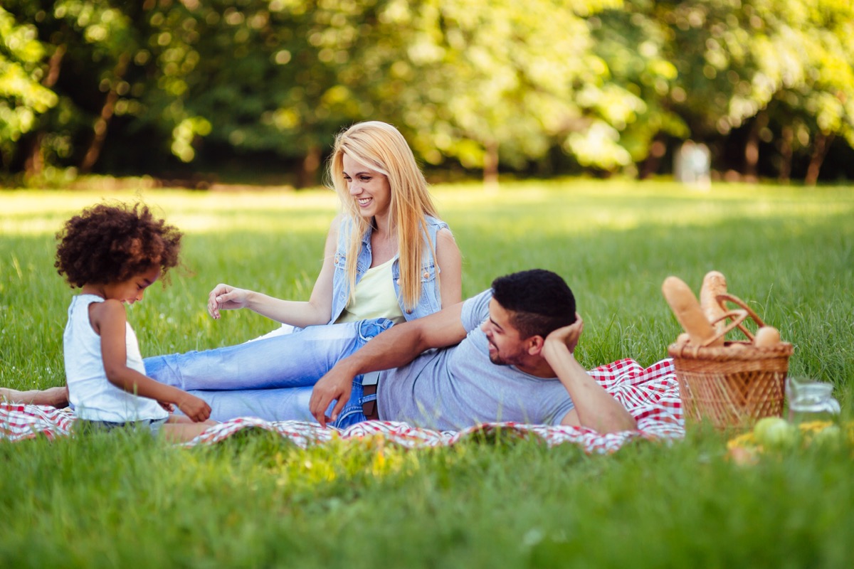 white woman and latino man with young daughter having a picnic outside