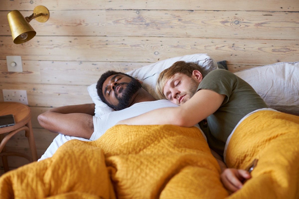 gay male couple cuddling together in bed