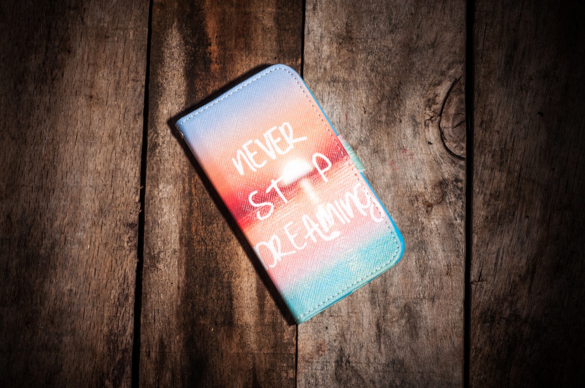 a phone case with the saying "never stop dreaming" on top of a beach sunset photo