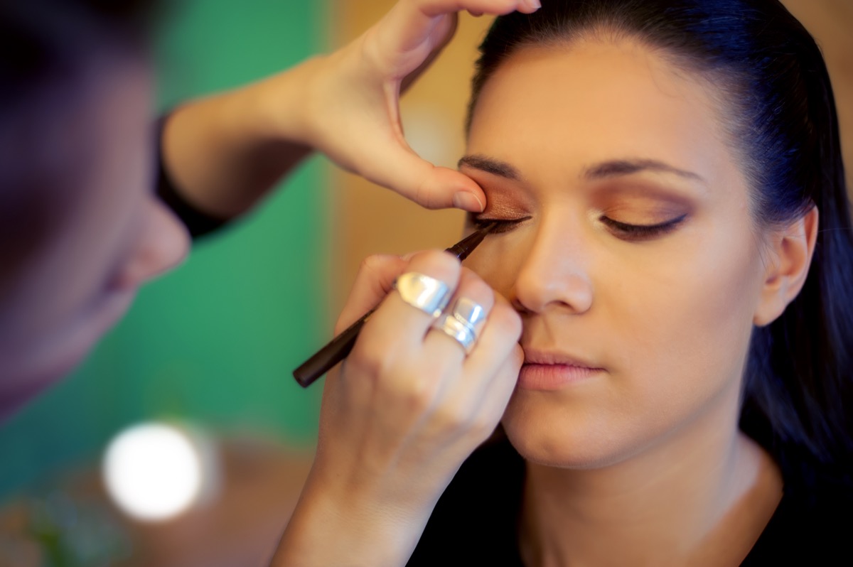 Makeup artist applies liquid eyeliner to woman's face